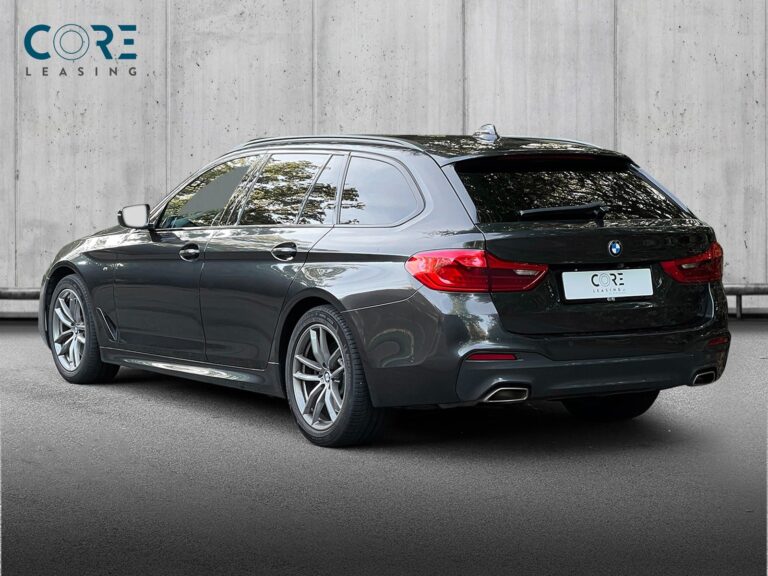 Gråmetal BMW 540i Touring M-Sport xDrive aut. fra 2019 parkeret foran en betonmur. CORE Leasing A/S er eksperter i BMW leasing.